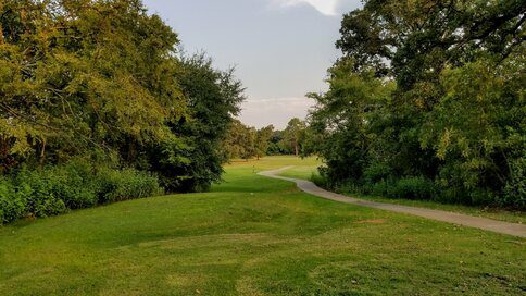 A scenic view of Hearne Golf Course, featuring well-maintained greens and trees under a clear sky.