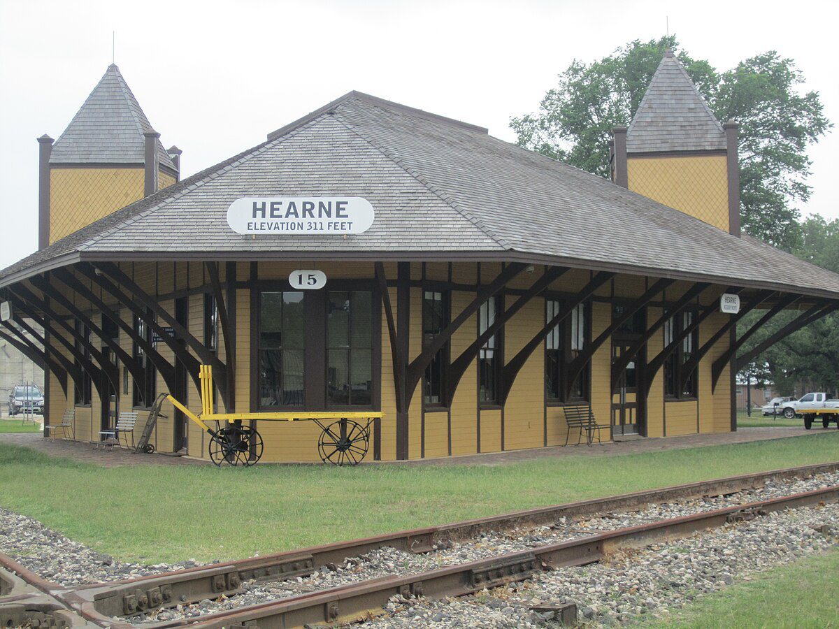 Historic Hearne Depot Museum with yellow exterior and railroad tracks in the foreground.