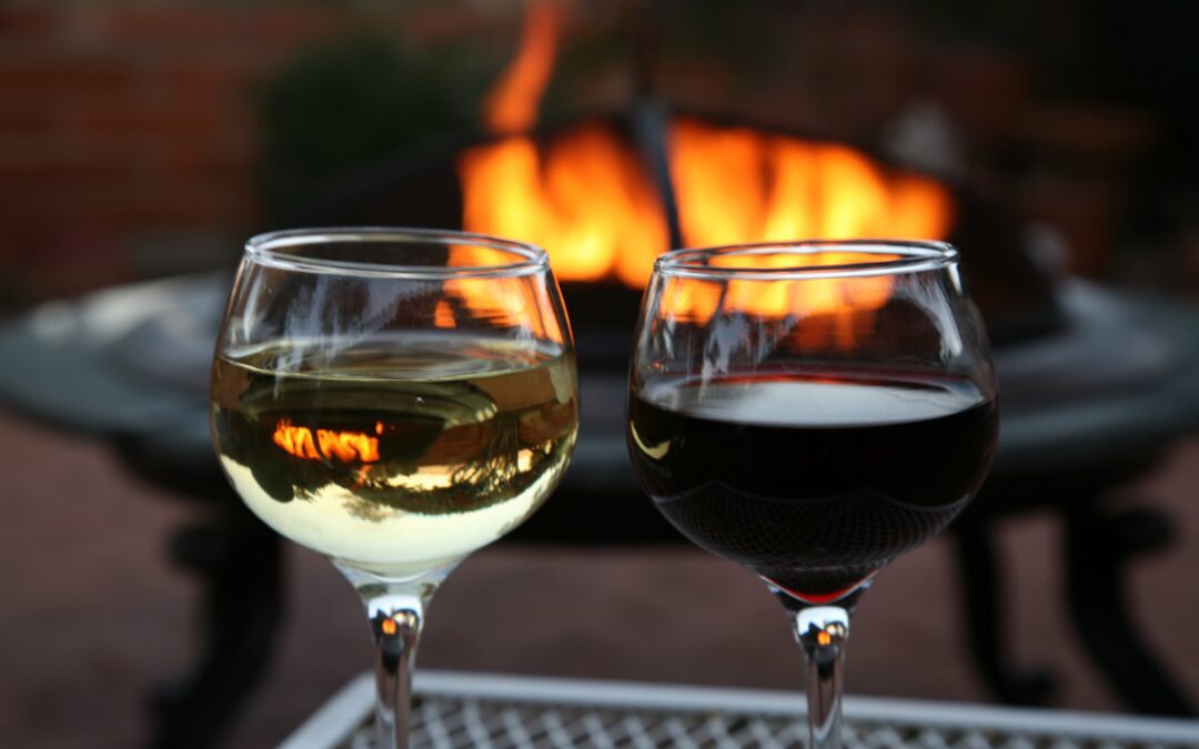 Two glasses of wine by a fire pit on a cozy winter evening at Galloping Snail RV Park in Bryan, Texas