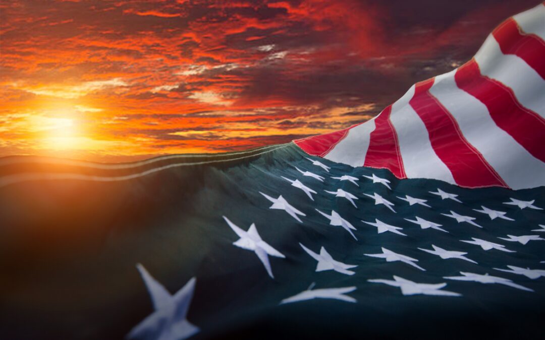 American flag waving against a dramatic red and orange sunset sky for Memorial Day weekend in Bryan Texas